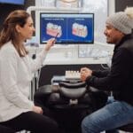 Dentista explicando las diferencias entre un inlay y un empaste dental a un paciente hispano en Virginia