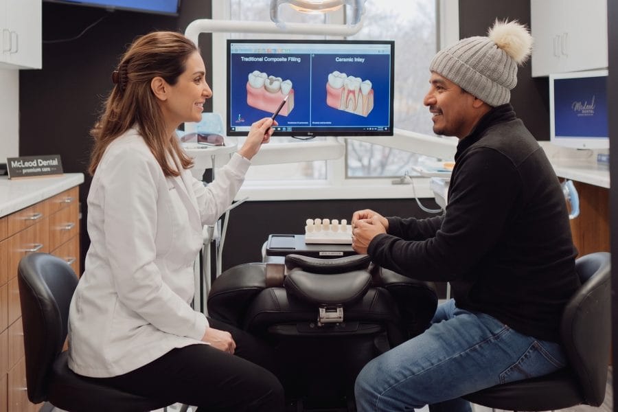 Dentista explicando las diferencias entre un inlay y un empaste dental a un paciente hispano en Virginia