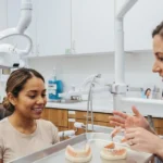 Dentista mostrando las diferencias entre una prótesis flexible y una prótesis parcial removible metálica a una paciente en una clínica dental de Virginia