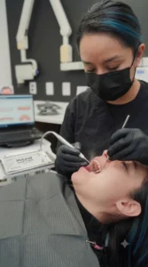 Higienista dental realizando una limpieza dental profunda para eliminar sarro bajo las encías