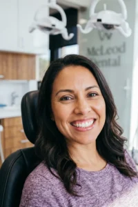 Paciente hispana sonriendo después de una limpieza dental profunda con encías saludables y dientes limpios